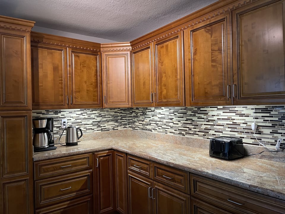 Coffee maker, water kettle, toaster. Kitchen has under cabinet lighting