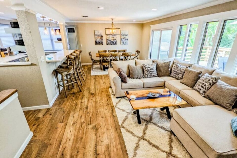 The living room is bright and cozy. With natural wood flooring and seating throughout.