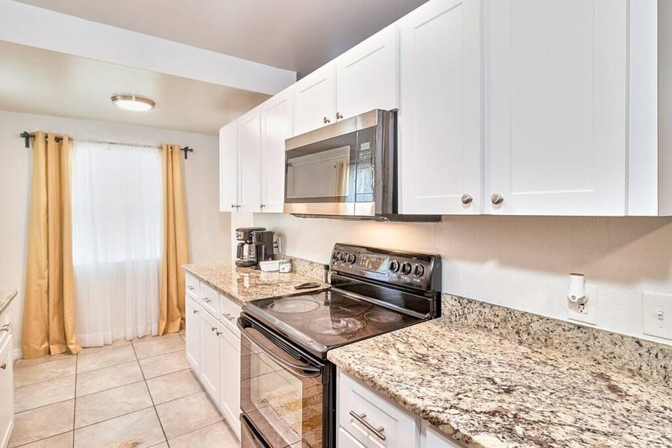 The kitchen features a spacious cabinet, stove, microwave, coffee maker, and toaster