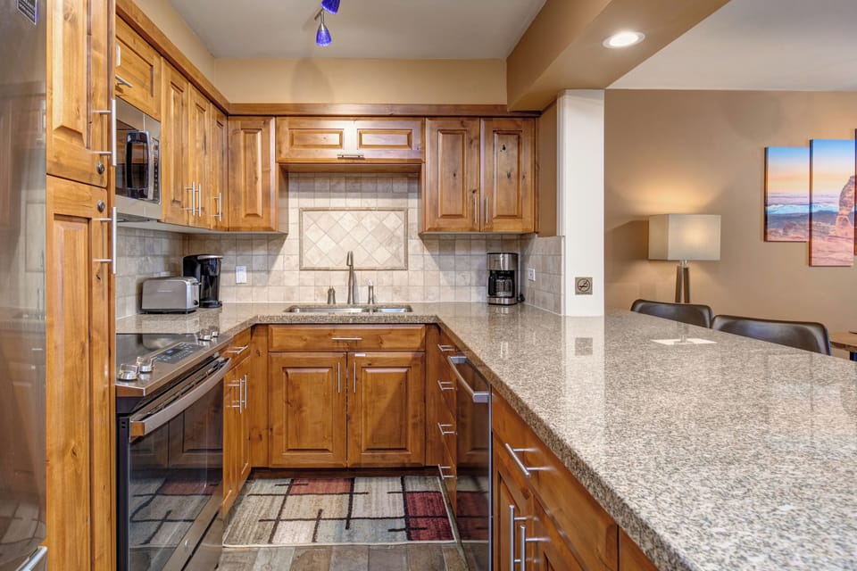 Your fully equipped kitchen features warm wood cabinetry, granite countertops, and modern appliances - perfect for preparing meals during your stay.