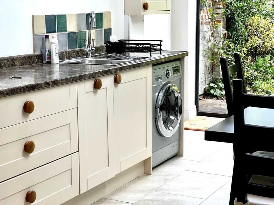 A functional kitchen space equipped with a washing machine, ample counter space, and a charming tiled backsplash.