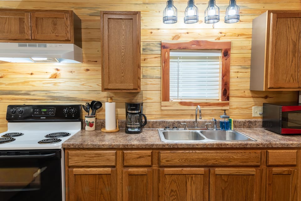 Double stainless sink, toaster, coffee maker, oven, stove, pots, pans, utensils
