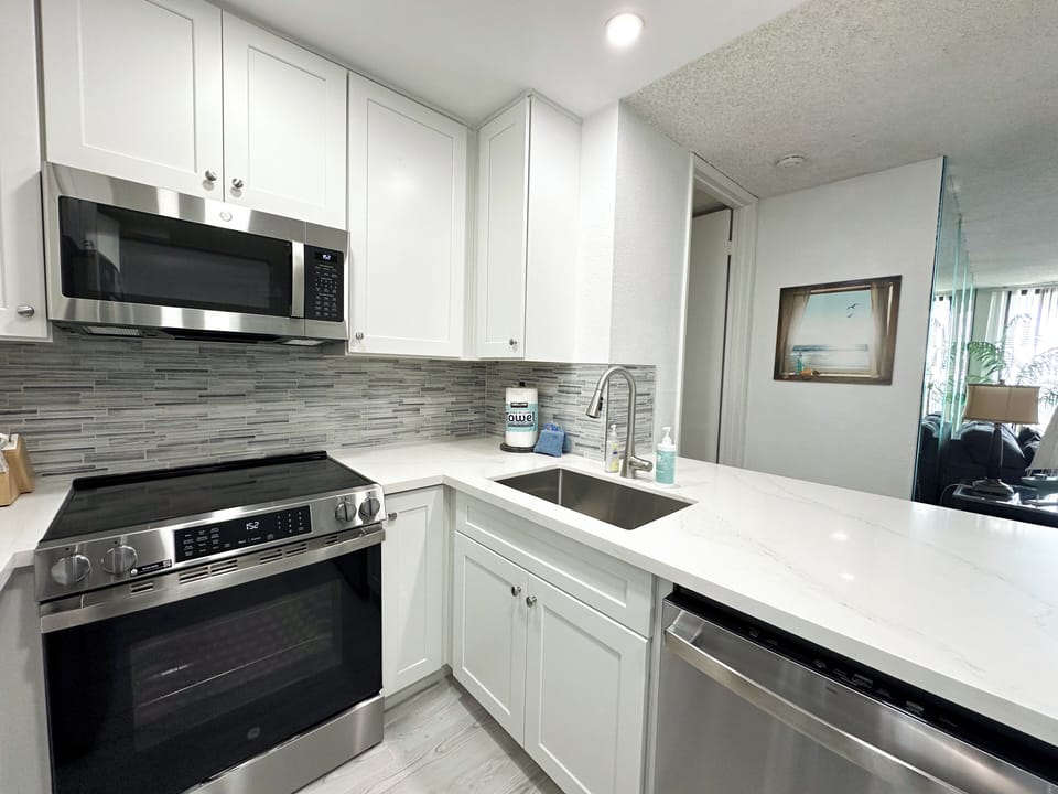 Kitchn remodeled with all-new white cabinetry, quartz countertops, and a custom backsplash.