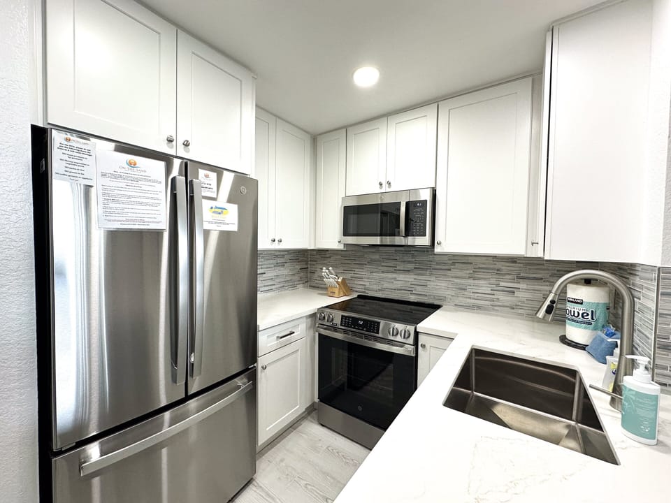 Fully stocked kitchen with all-new stainless steel appliances, including refrigerator, oven, dishwasher, and microwave (January 2026).