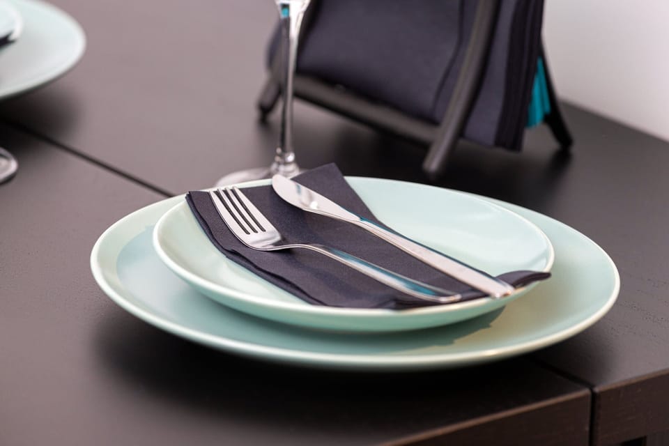 A small round dining table with minimalist tableware and a decorative piece.
