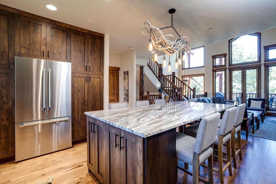 Your gourmet kitchen features rich wood cabinets, marble island seating, and mountain views perfect for memorable meals together.