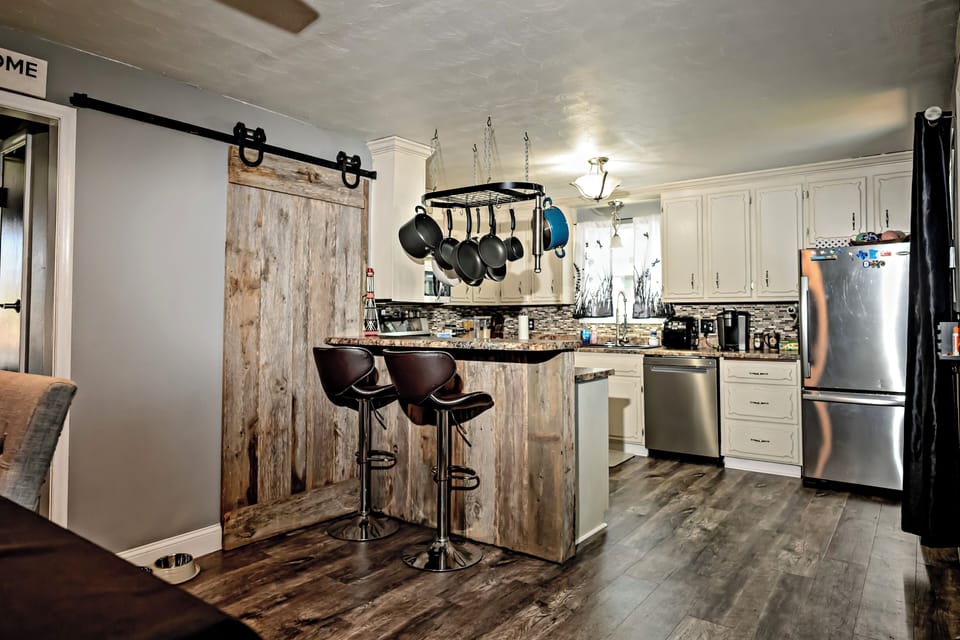 Rustic bar seating and barn door charm in open kitchen layout.