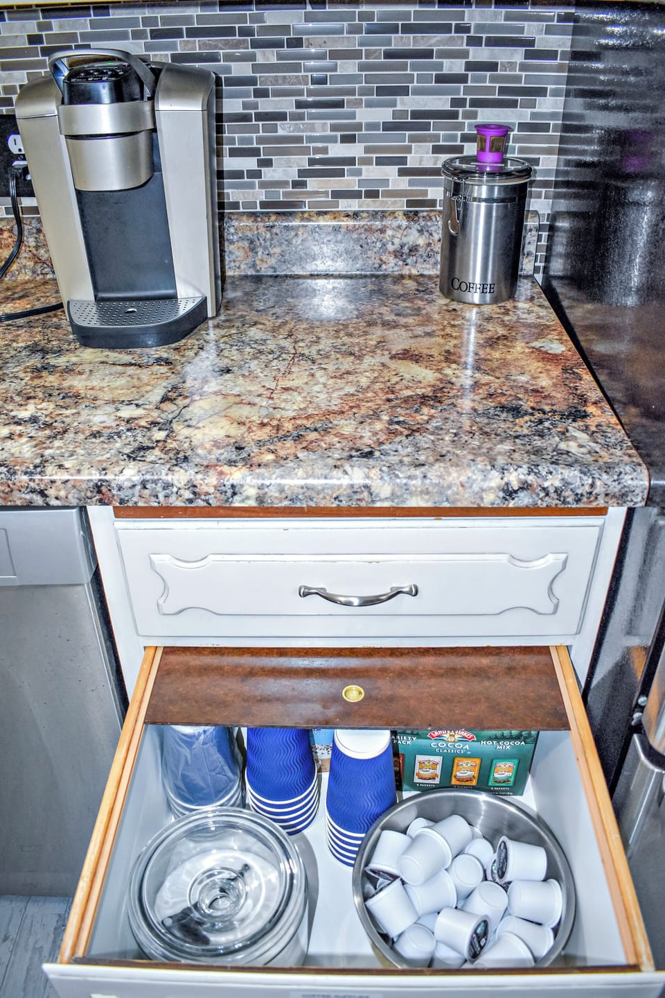 Coffee bar stocked with pods, cocoa, and to-go cups.