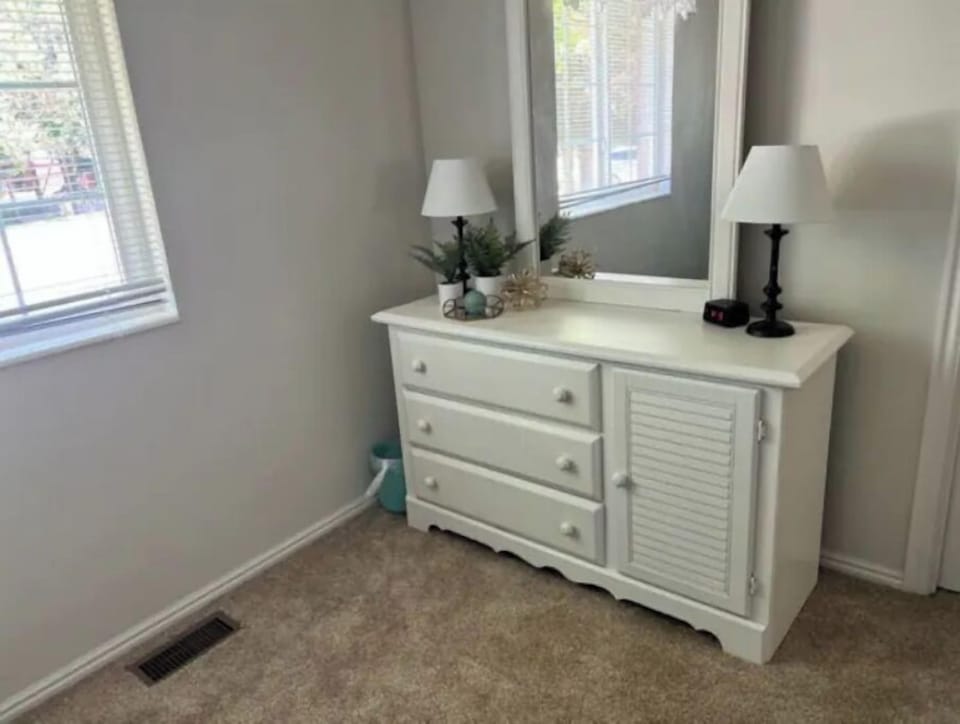 Dresser with mirror, lamps, and alarm clock.