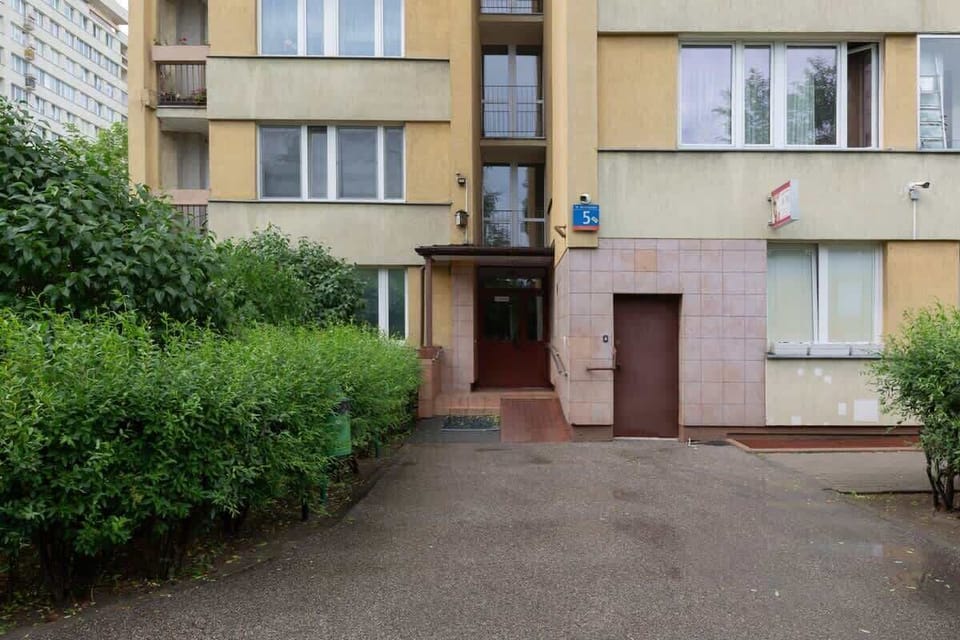 Clean and tidy entrance to the building next to which there are many greenery.