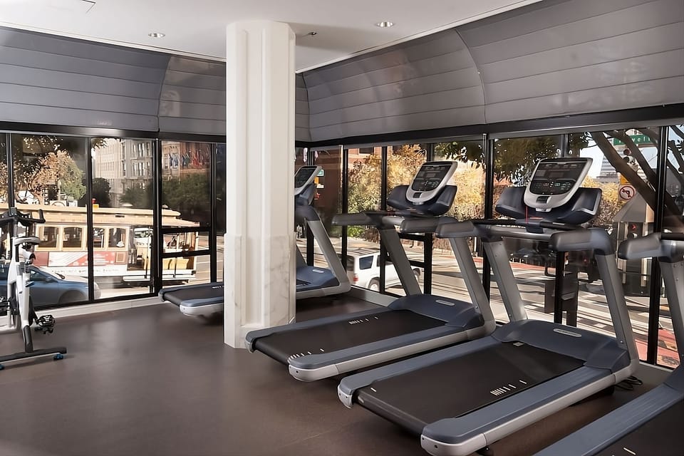 Recharge with a quiet run on treadmills beneath tall windows.