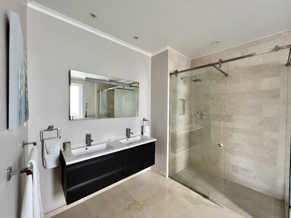 Full en-suite with a floating double sink vanity with storage and hair dryer.