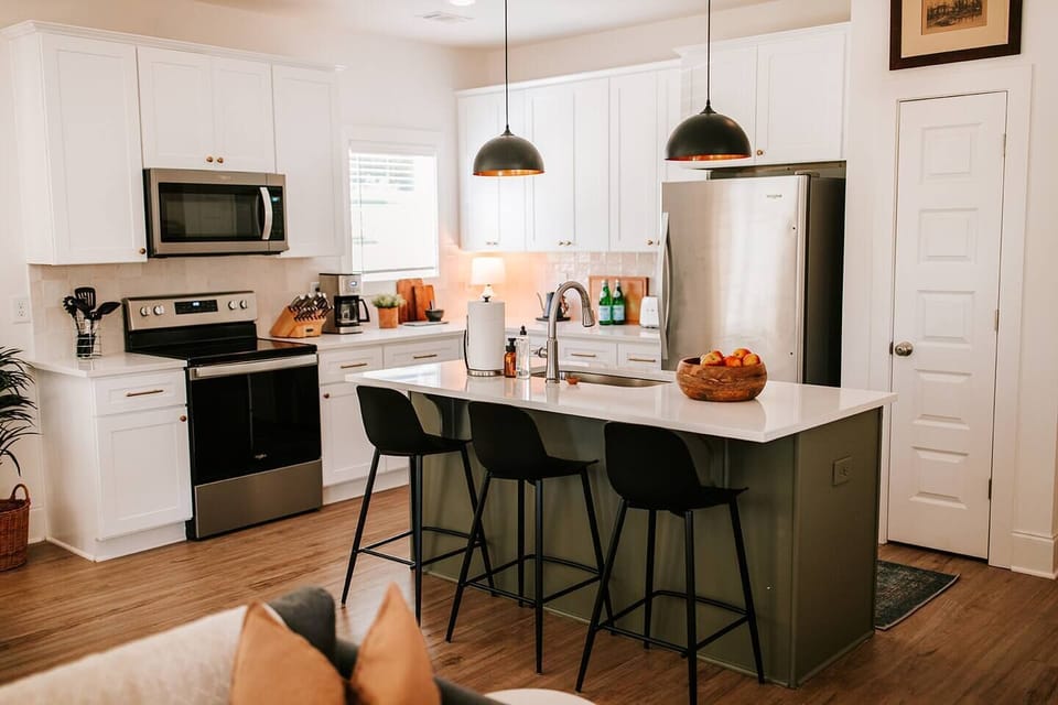 Modern elegance meets functionality: This luxurious kitchen features stainless steel appliances and an island with seating for three, ideal for entertaining guests while preparing gourmet meals.