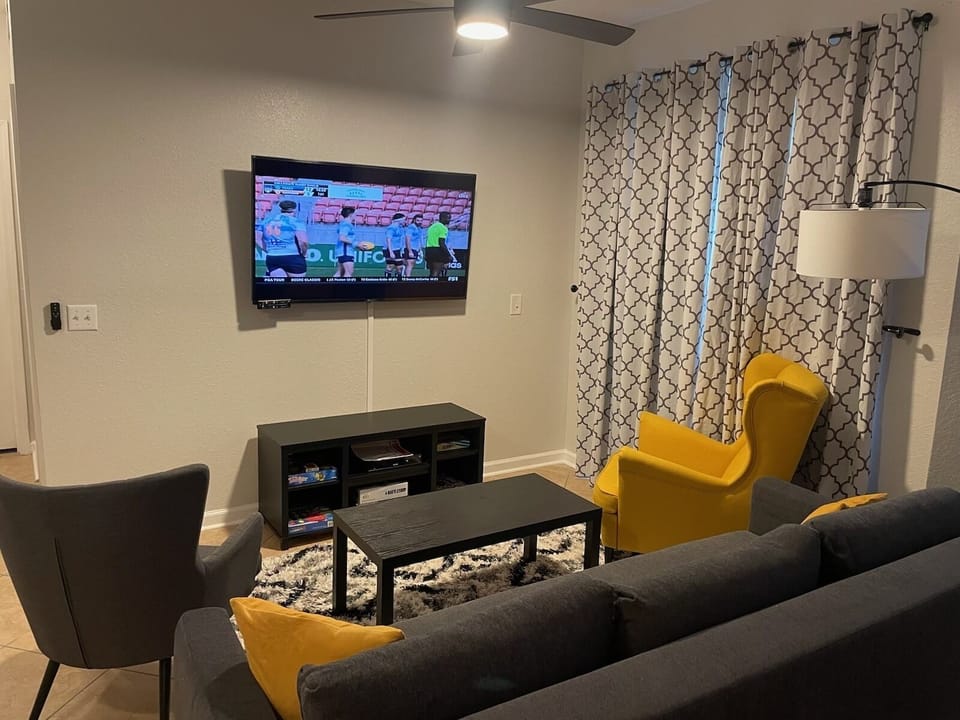 Living room with Smart TV and Smart ceiling fan.  Curtains cover sliding doors 