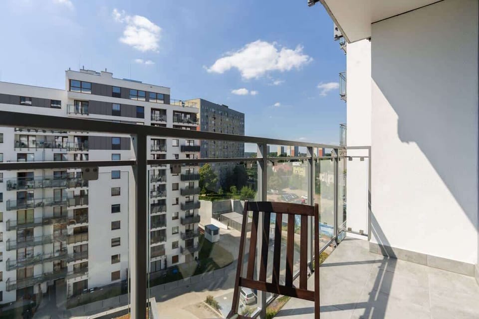 A balcony with outdoor seating overlooking a green and urban area, providing a perfect spot for relaxation.