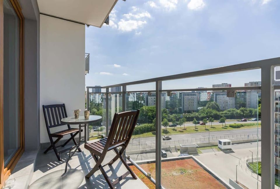 A balcony with outdoor seating overlooking a green and urban area, providing a perfect spot for relaxation.