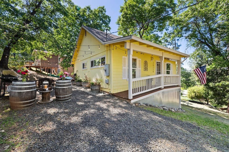 Front of Brodie Cabin with covered porch, side yard seating, BBQ grill, and fire pit area. Peaceful Tuolumne setting near Yosemite — perfect for outdoor dining, evening fires, and enjoying the surrounding forest views.