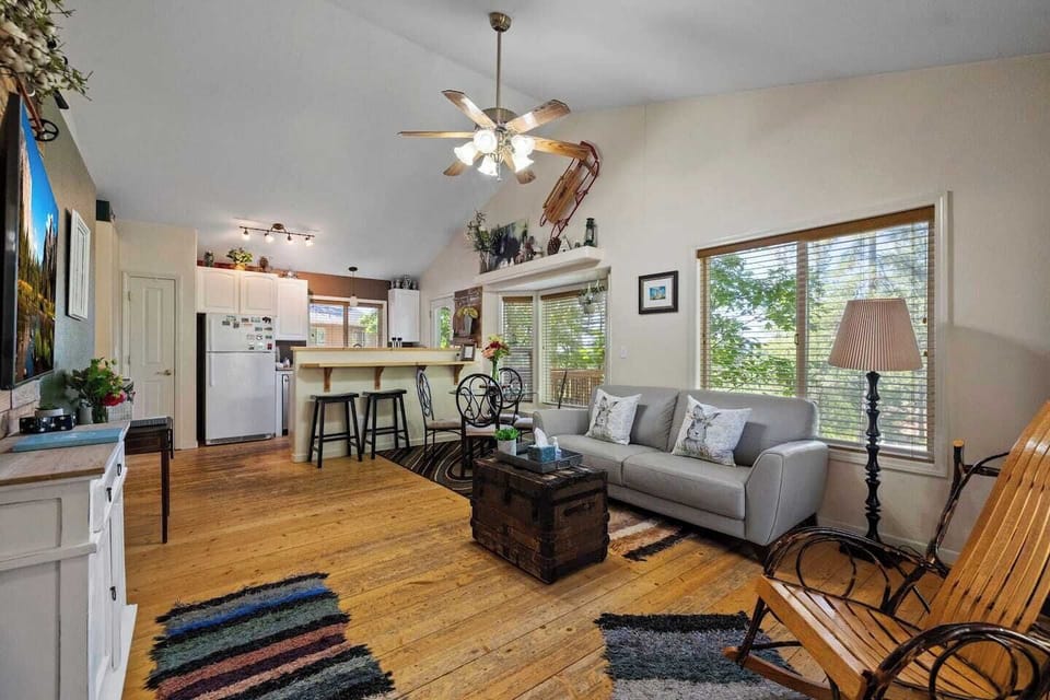 Open-concept living area with high ceilings, leather sofa, dining table for four, and kitchen bar with stools. Features quartz countertops and a fully stocked kitchen — ideal for Yosemite visitors and Tuolumne stays.