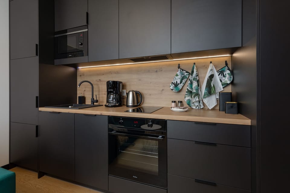 A modern kitchen with black cabinets, a wooden worktop and high-quality appliances provides a convenient place to cook.