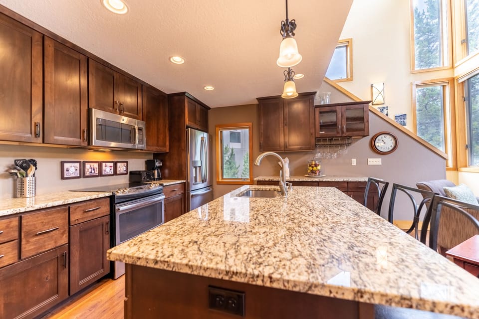 Full-sized kitchen featuring stainless steel appliances, granite countertops, kitchen island, and hardwood floors.