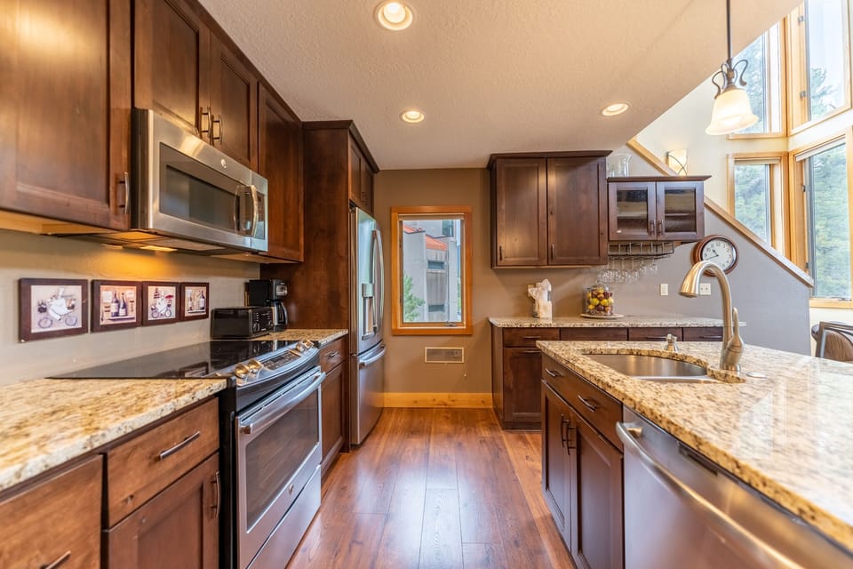 Full-sized kitchen featuring stainless steel appliances, granite countertops, kitchen island, and hardwood floors.