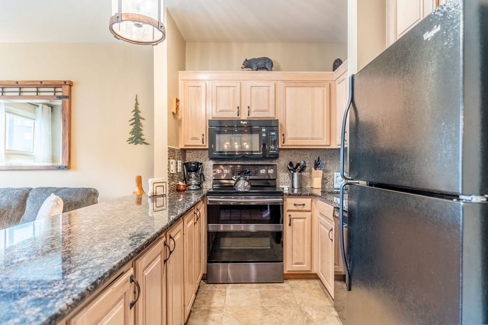 Full size kitchen with granite countertops and stainless steel appliances.