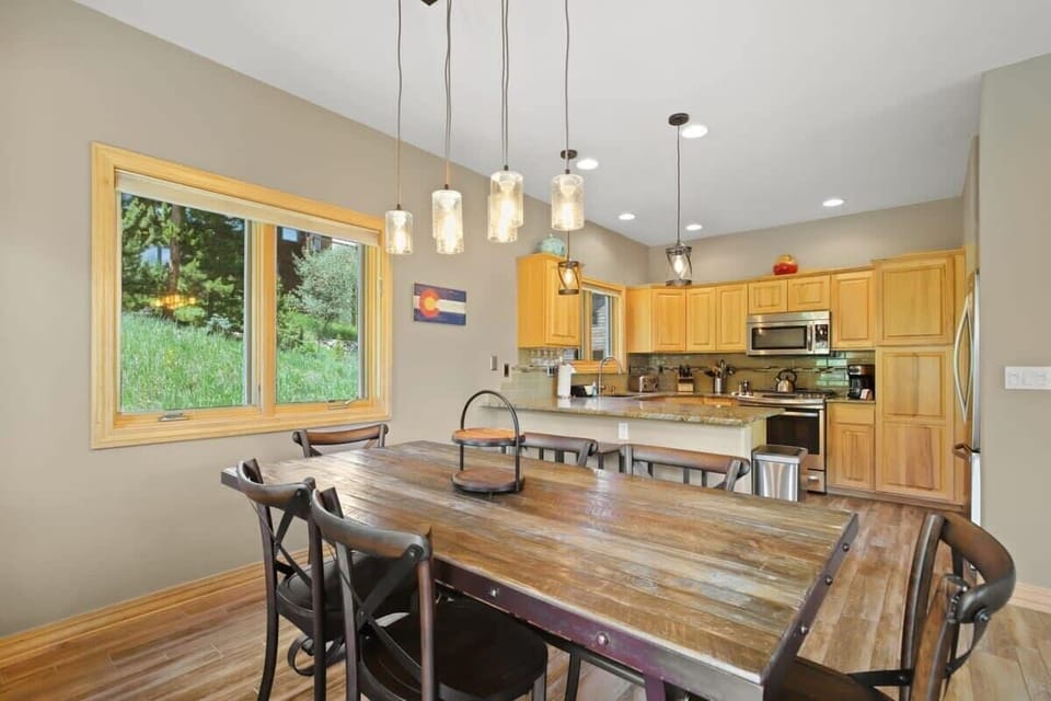 The dining table features pendant lighting and seating for six, with seats for three more at the nearby bar.