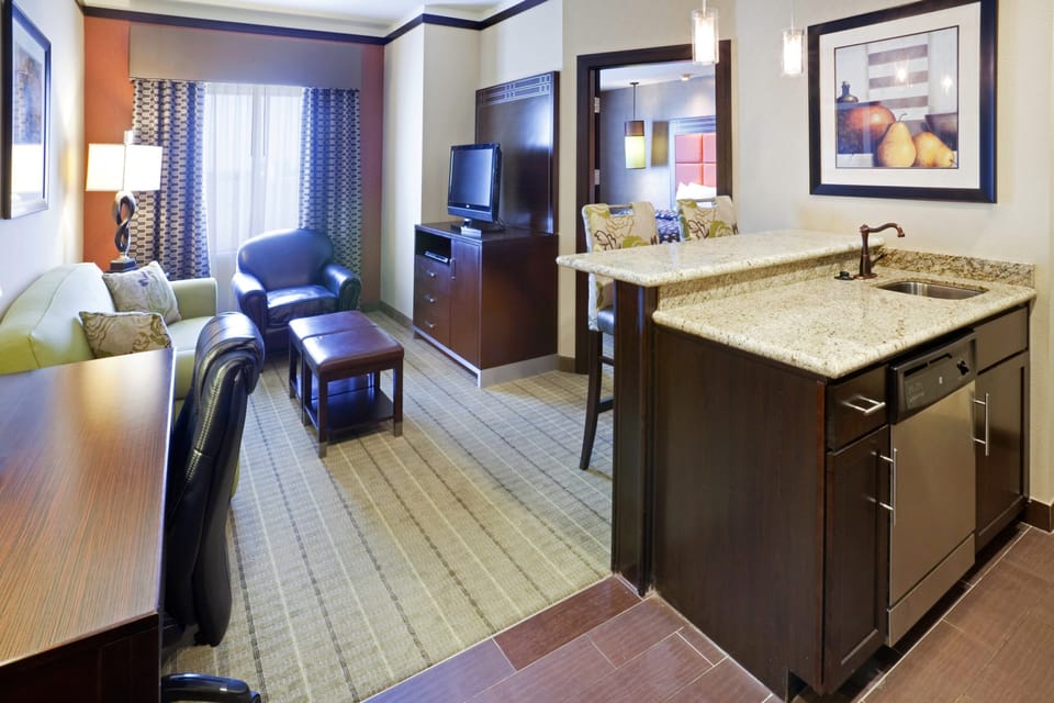 Living area with kitchen, sofa, chairs, and TV