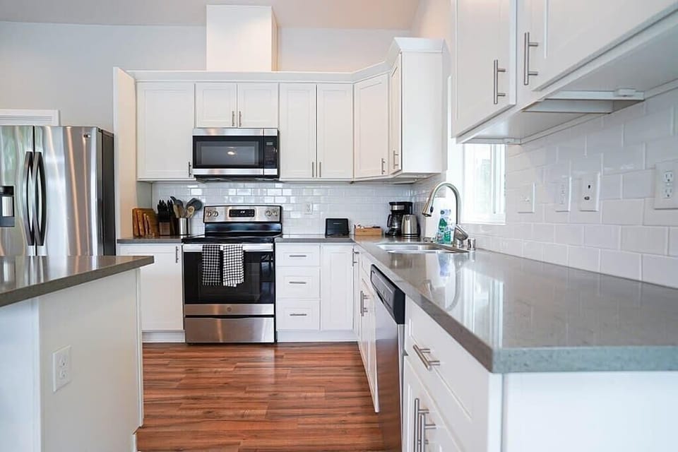 The fully equipped kitchen features stainless steel appliances, a center island with bar seating, and a luxury tiled backsplash
