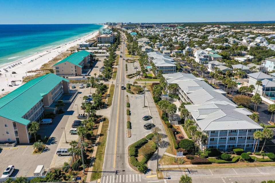 Aerial view of a stunning beachfront community with pristine white sand beaches and turquoise Gulf waters stretching endlessly along the coast.
