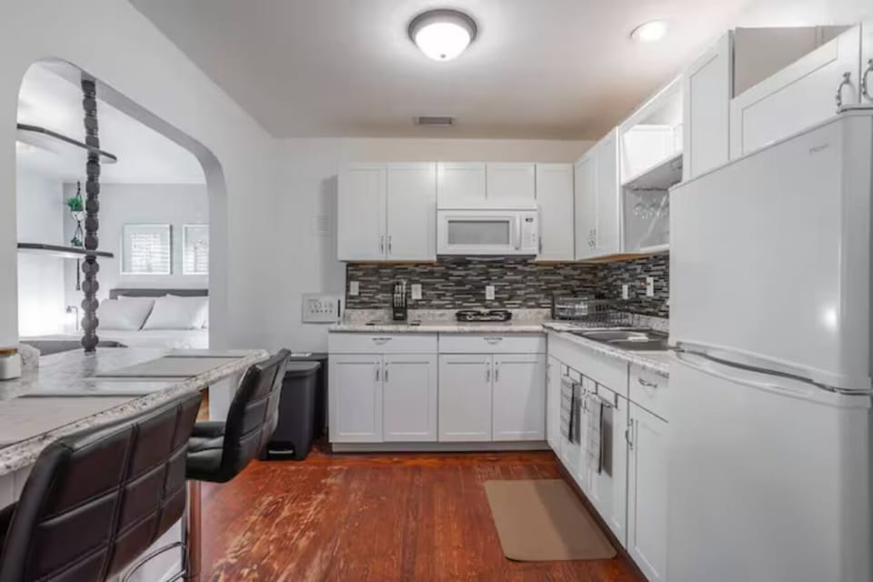 kitchen with cabinets, microwave, refrigerator, small two-place stove, bar and chairs