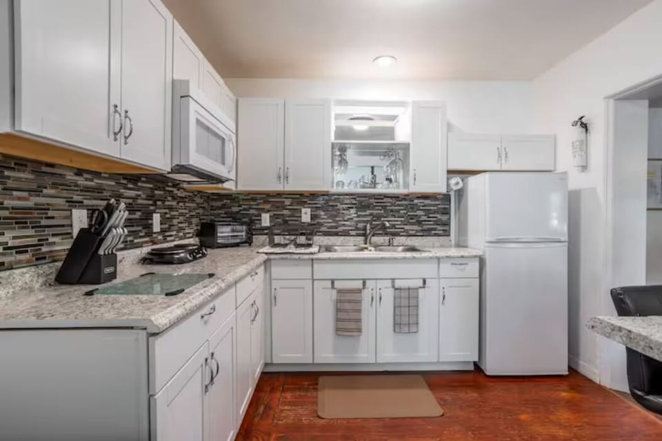 kitchen with cabinets, microwave, refrigerator, small two-place stove, bar and chairs