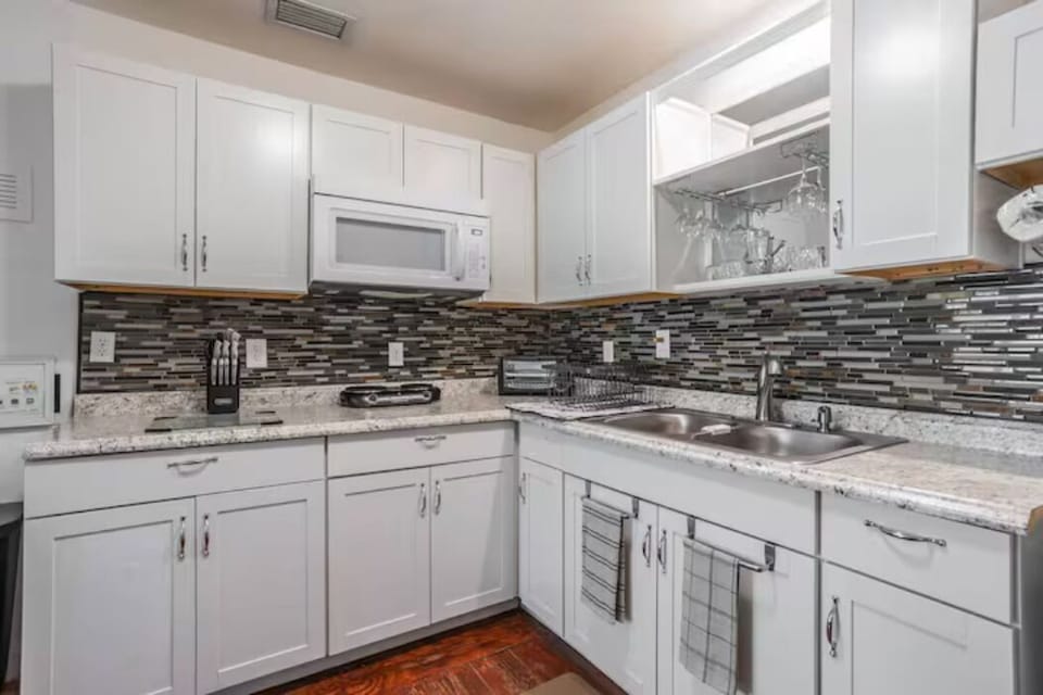 kitchen with cabinets, microwave, refrigerator, small two-place stove, bar and chairs