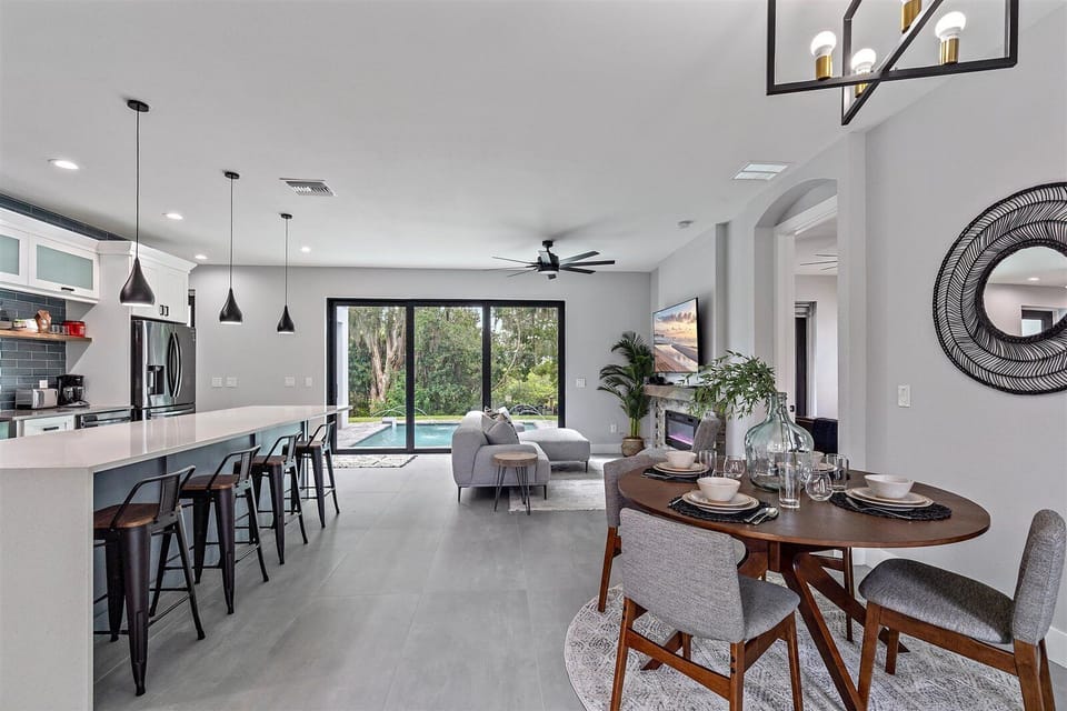 Cook, dine, and connect in the open-concept kitchen and dining space overlooking the pool.