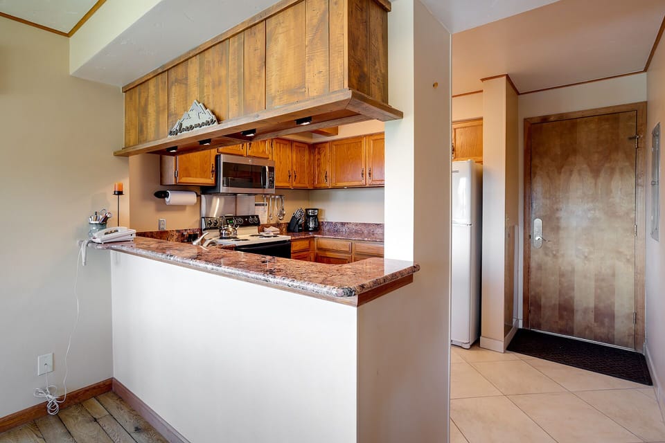 Whip up your favorite meals in this fully equipped kitchen featuring granite countertops, warm wood cabinetry, and modern appliances.