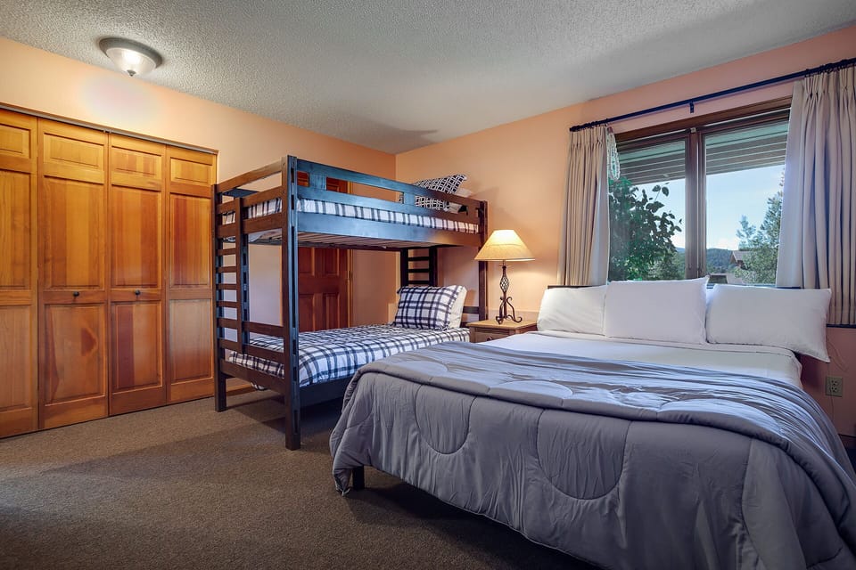 Your family bedroom features comfortable bedding and bunk beds, perfect for kids with mountain views through large windows.