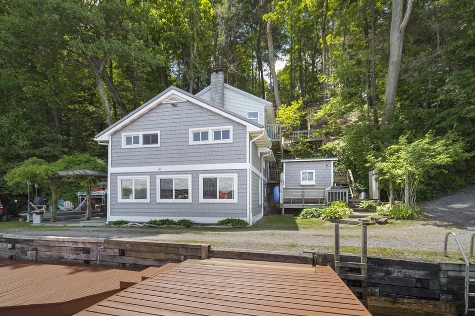 Cayuga Cottage, nestled lakeside surrounded by lush green.