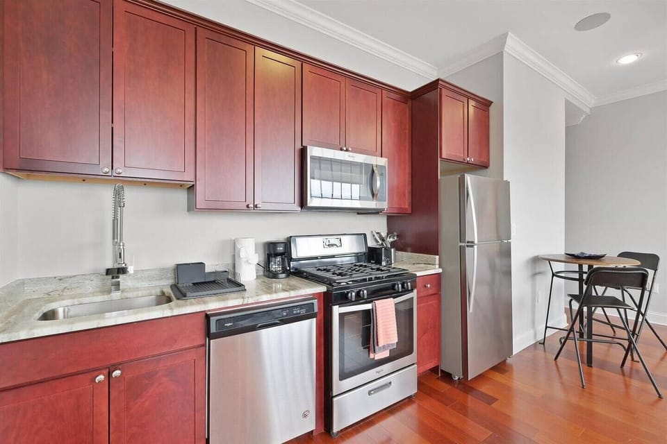 Kitchen featuring cherry cabinetry, stainless refrigerator, and complete cookware ready for meal preparation