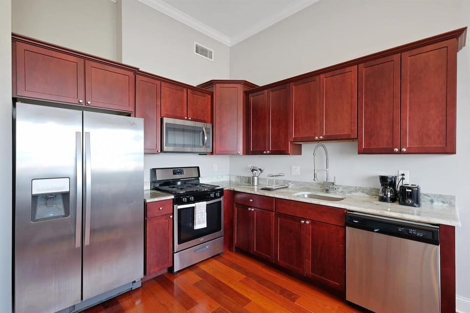 Full kitchen with cherry cabinets, gas range, and modern appliances providing all the tools for delicious meals