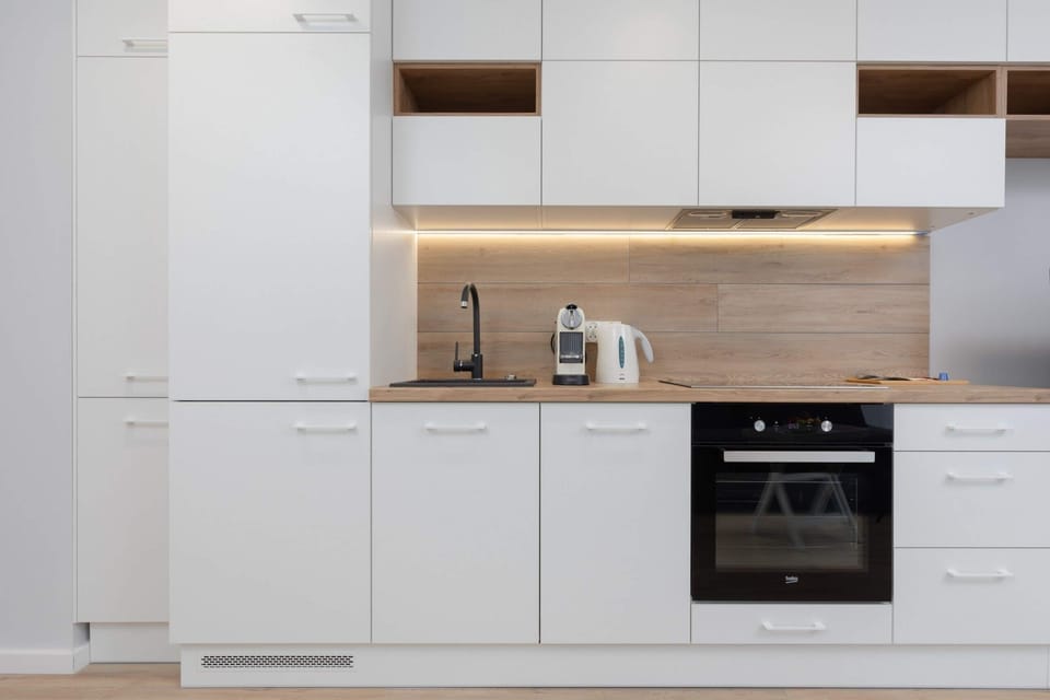 Kitchen with white cabinets containing all the necessary dishes as well as high-quality appliances such as an oven, coffee maker and fridge.