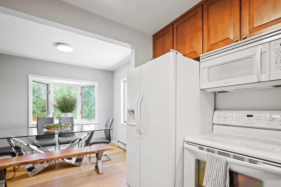 Just off of the kitchen, find the dining area that features a sleek, glass table with seating for eight and abundant natural light and mountain views thanks to the many windows that surround it.