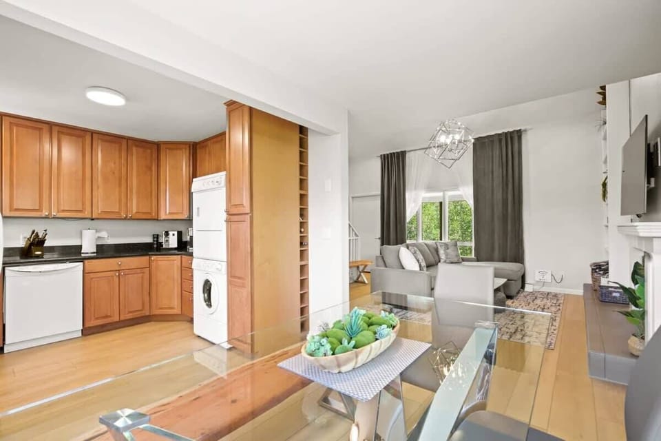 The charming kitchen boasts ample cabinets, modern black countertops, bright, white appliances, including a stacked washer and dryer, and everything you need to feel at home from a toaster to a coffee maker.