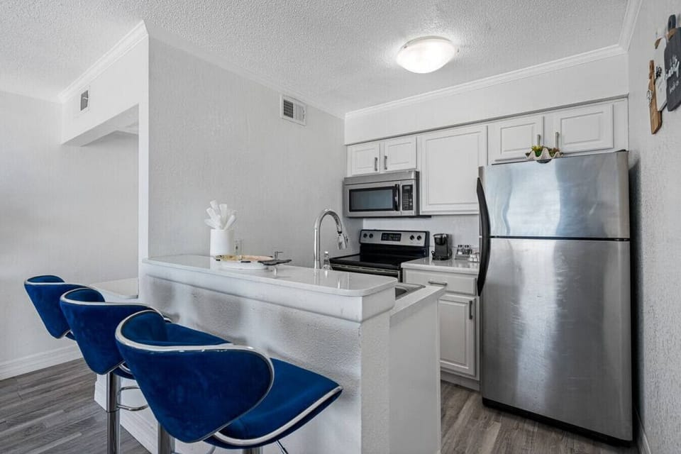 It features a fully equipped kitchen with all the essentials, including a fridge, stove, microwave, and silverware.