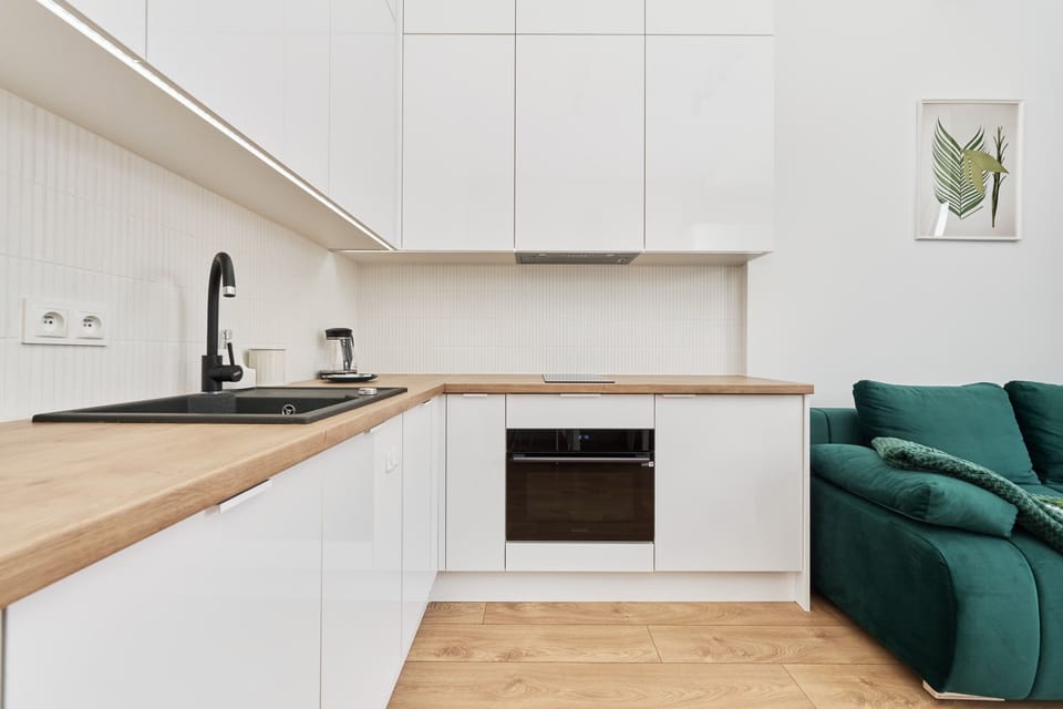A sleek white kitchen with integrated appliances and a minimalist aesthetic.