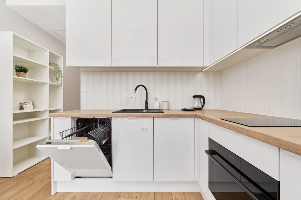 A sleek white kitchen with integrated appliances and a minimalist aesthetic.