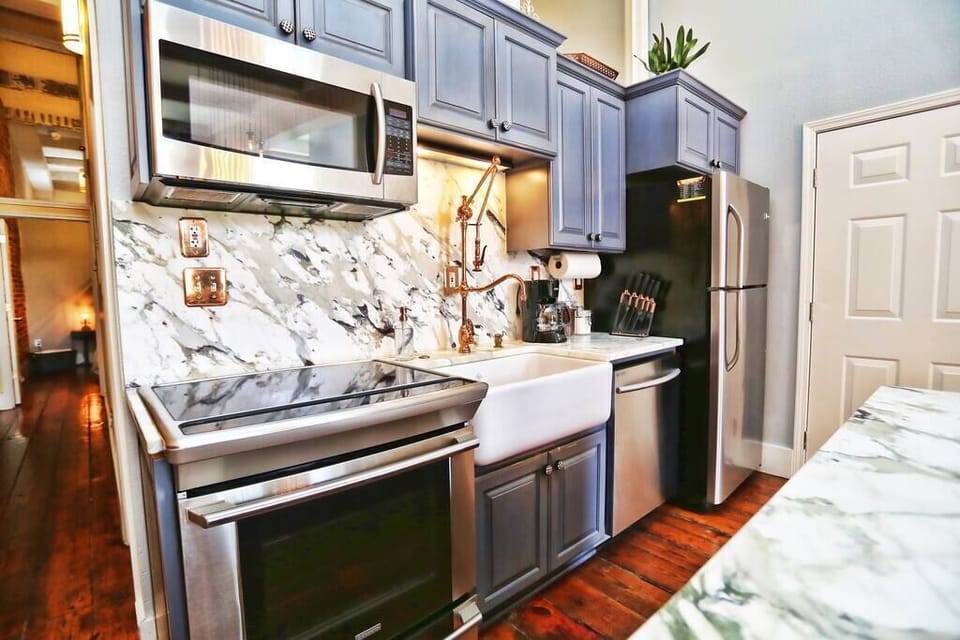 Kitchen with marble stone top counters and backsplash, custom made copper faucet, induction stove, dishwasher, large island and fridge/freezer.