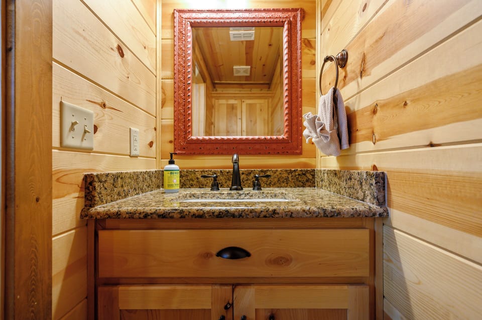 Warm wood paneling and a granite countertop create a cozy, rustic atmosphere. Fresh towels and thoughtful details await your arrival in this charming, nature-inspired space.