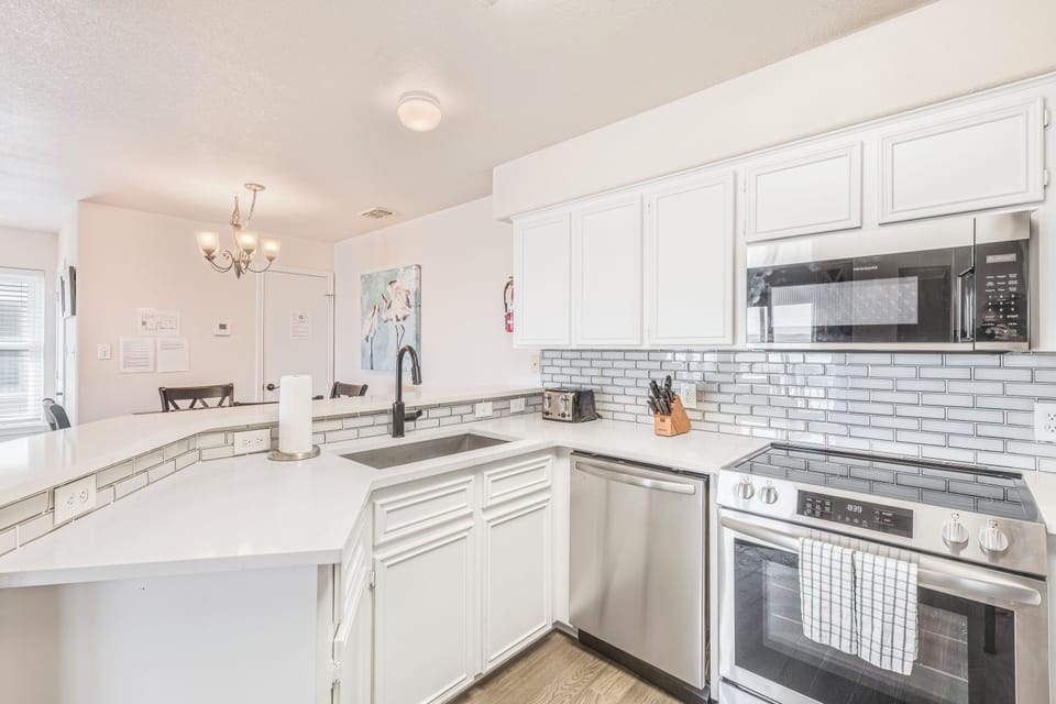 You'll love cooking in this bright, modern kitchen with pristine white cabinets, subway tile backsplash, and stainless steel appliances.
