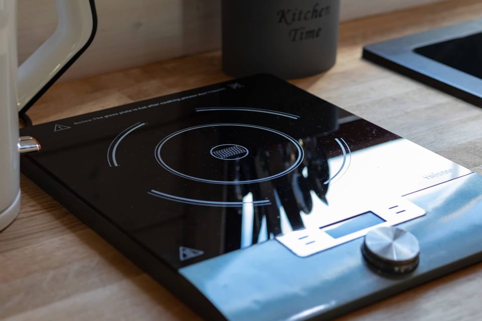 A modern electric stovetop with a sleek black surface, neatly integrated into the kitchen counter. The setup looks clean and easy to use for everyday cooking. Minimalist design adds to the overall contemporary feel.
