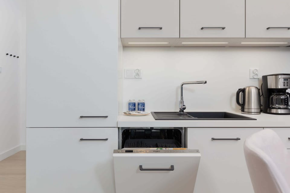 A modern kitchen area equipped with a fridge, stove, and sink with minimalist design